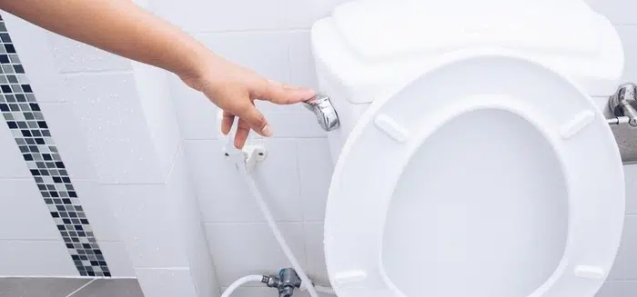 Person repairing the internal mechanisms of a running toilet