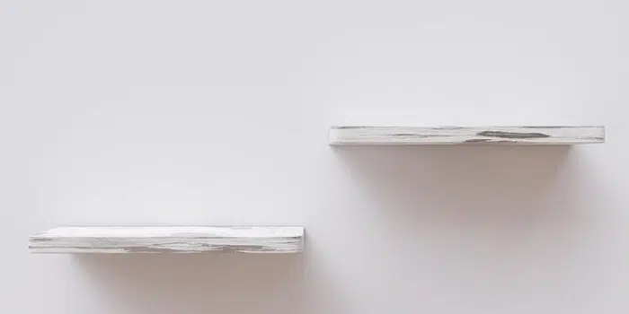 Person installing floating shelves on a living room wall
