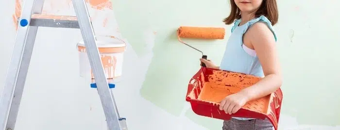 Young woman painting a bedroom wall with a roller brush