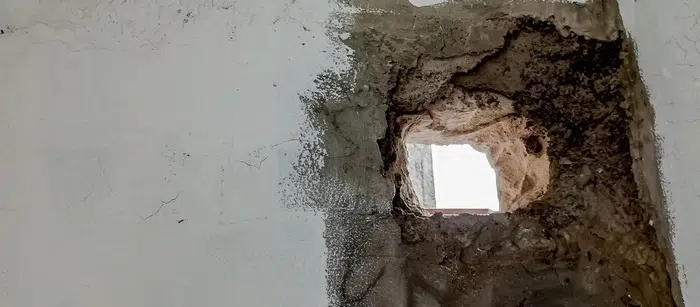 Person patching a hole in drywall using a putty knife and spackle