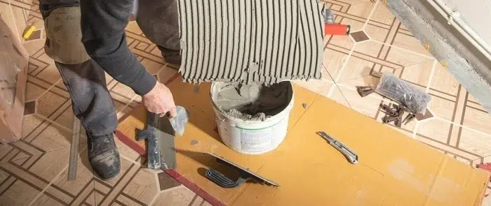 Person applying new grout between bathroom tiles with a grout float