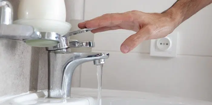 Person installing a new faucet in a modern kitchen sink