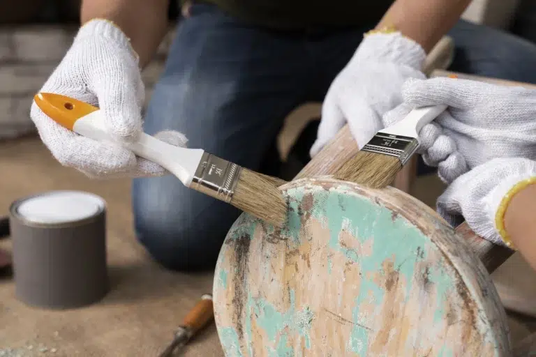 Person holding a paintbrush while working on a DIY project