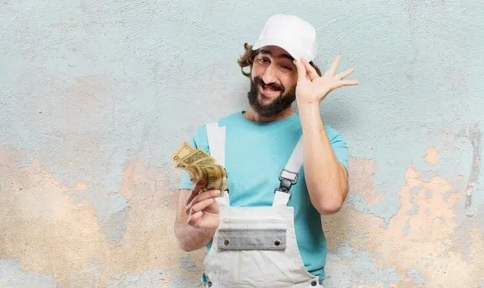 Man smiling as he completes a DIY project at home, surrounded by tools, showing cost savings