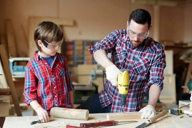Father and son working on a woodworking project together indoors, focused and dressed casually